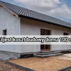 Szary dom w trakcie budowy, z widocznym dachem i oknami. Na fasadzie tekst: "Jaki jest koszt budowy domu 100 m²?".
