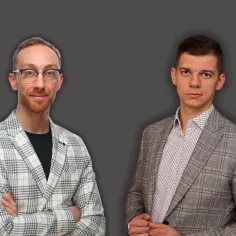 Dwóch mężczyzn w garniturach. Jeden w okularach, drugi z zapiętą marynarką. Ich wspólna roboczogodzina przynosi sukces.