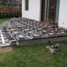 Budowa tarasu kompozytowego w toku. Widać betonowe bloczki i legary, które wyznaczają co ile legary pod taras kompozytowy.