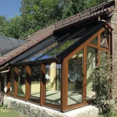 Nowoczesny ogród zimowy na tarasie, z drewnianymi ramami i przeszklonym dachem, idealny do relaksu przez cały rok.